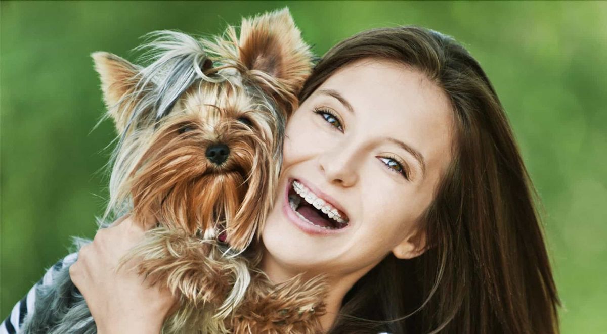 Smiling woman with small dog outdoors.