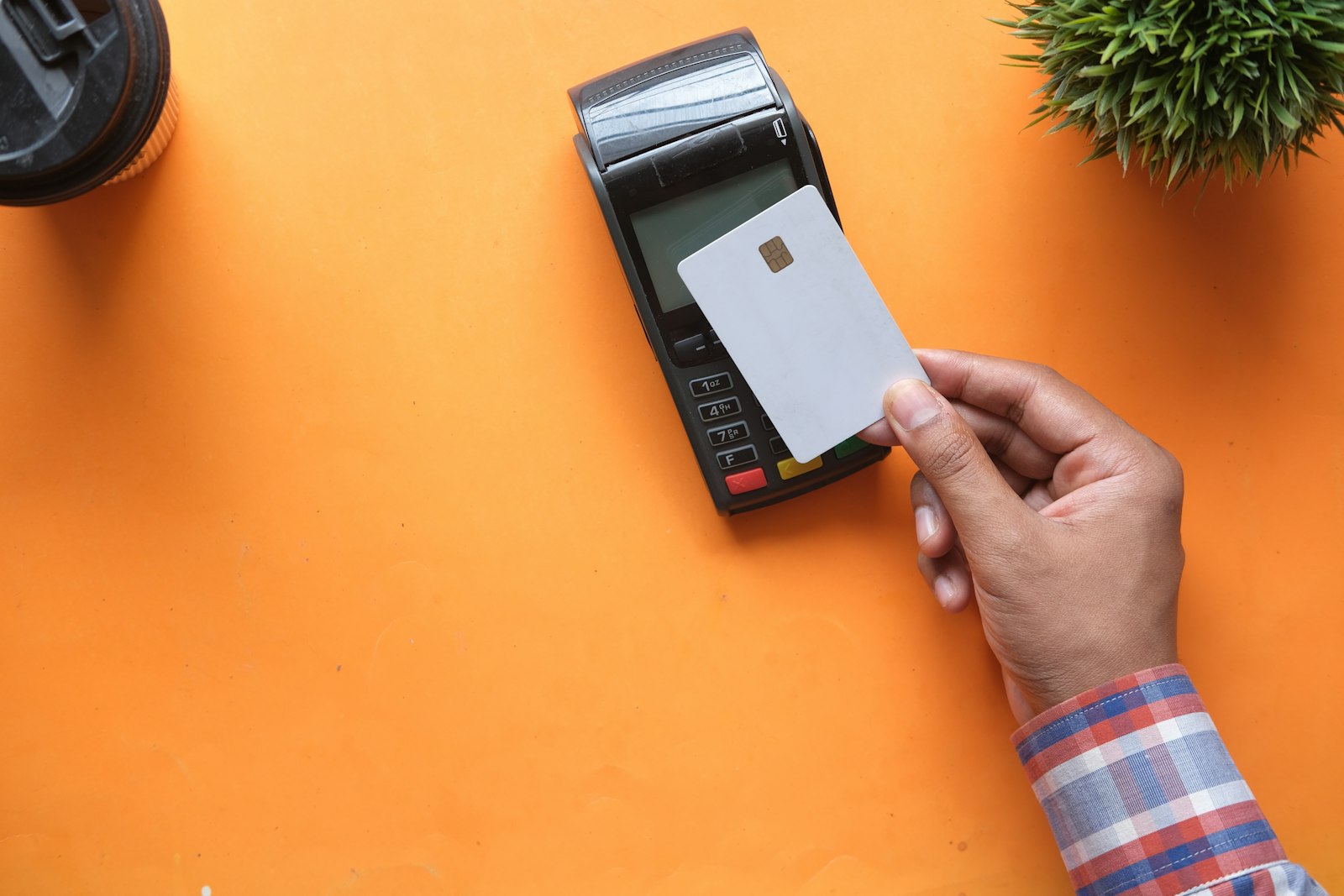 Hand tapping a payment card on a card reader.